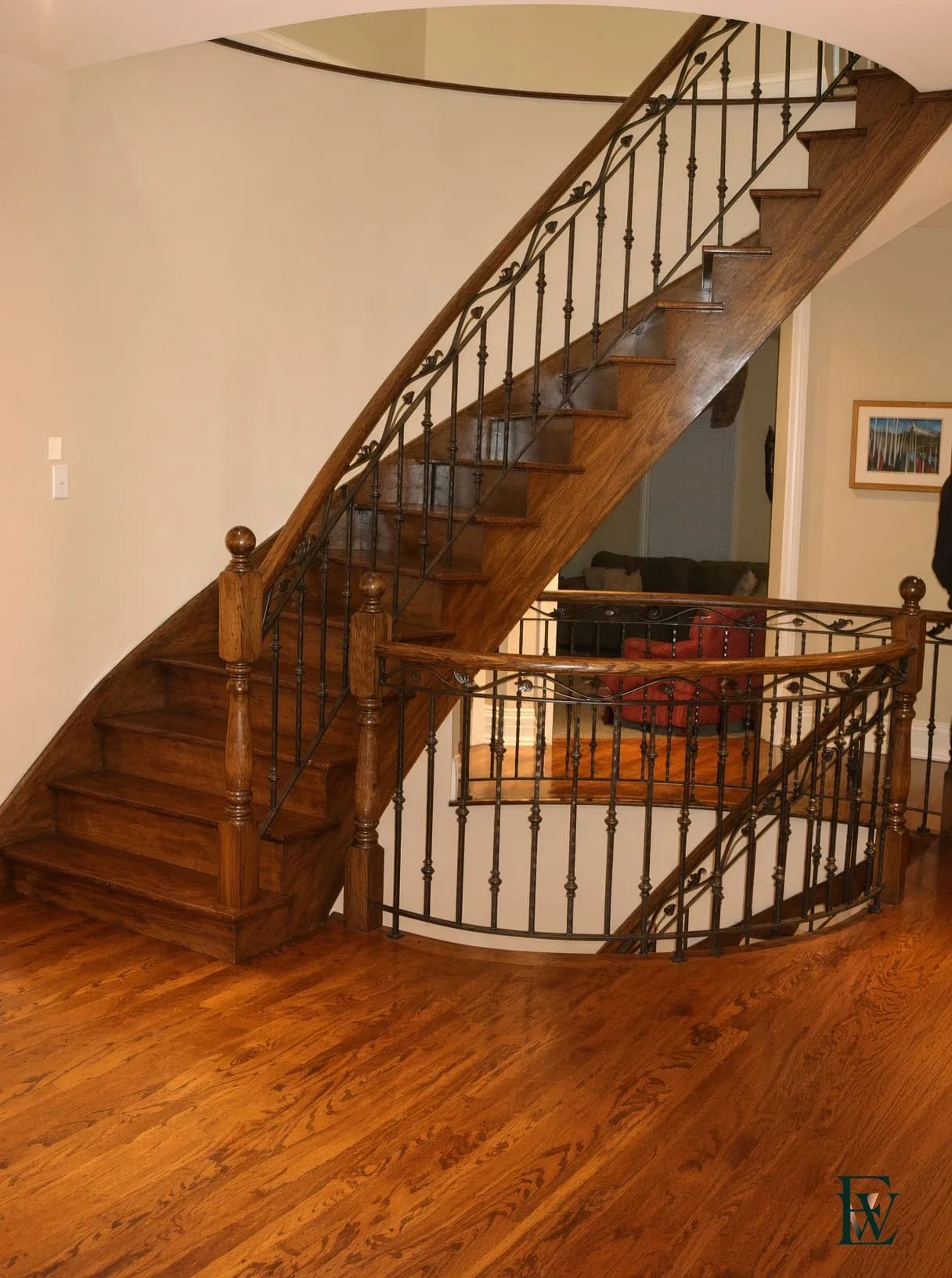 Curved oak stair with a bent handrail and ornamental iron balustrade, frame 1 of 3, full flight view from the foot of the stair, Ecowoods site work, Toronto.