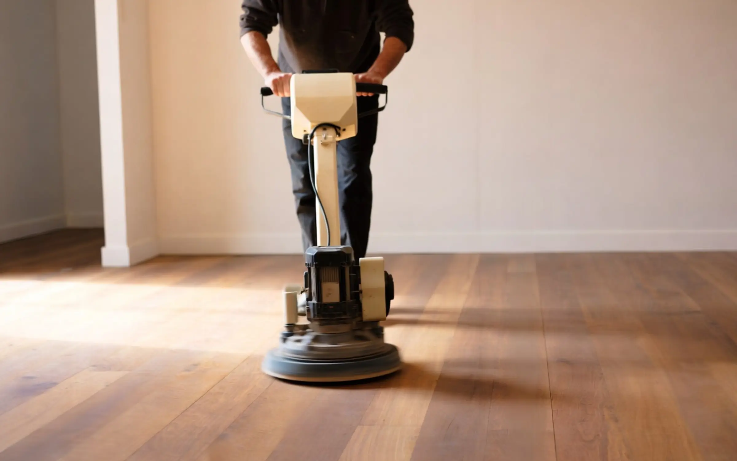 Rotary buffer polishing a hardwood floor between finish coats